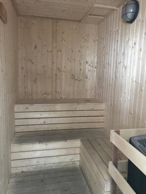 Un sauna en bois avec un banc et des marches.