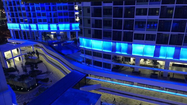 Un hotel de varios pisos con un diseño moderno, que presenta un patio central con zonas de estar y una estatua.