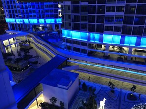 Un hôtel à plusieurs étages au design moderne, doté d’une cour intérieure avec des espaces aménagés pour s’asseoir et une statue.