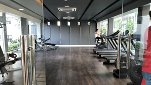 Un gimnasio con cintas de correr, máquinas de pesas y un amplio ventanal que proporciona luz natural.