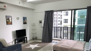 Habitación de hotel con televisión, dos camas, alfombra con estampado de estrellas, estante vertical y balcón con vistas a edificios.