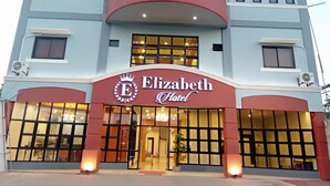 Et hotel med et tydeligt skilt, der viser 'Elizabeth Hotel', store vinduer og klimaanlæg på facaden.