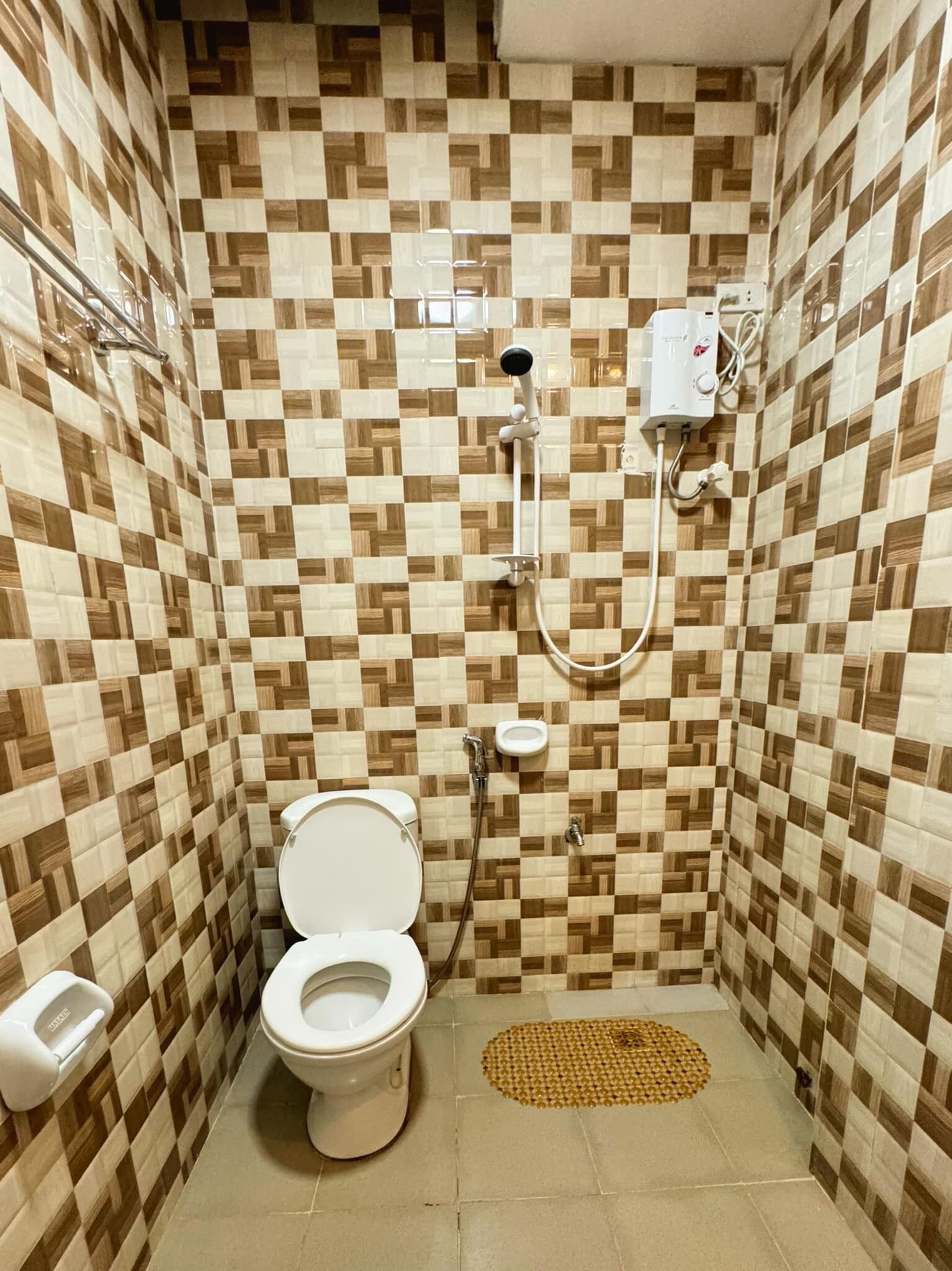 A small, tiled bathroom with a toilet, a shower, and a hand dryer.