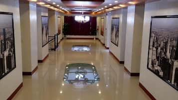 Un pasillo de hotel con piso brillante, cuadros en las paredes y un candelabro.