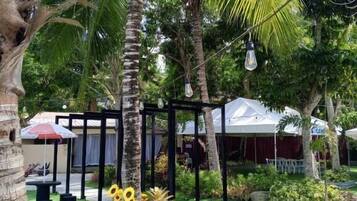 A tropical garden with palm trees, a gazebo, and a paved walkway.
