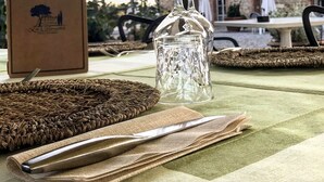 Une table dressée avec une carafe en verre, une serviette pliée et un menu posé sur une nappe.