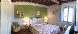A bedroom with a bed, two bedside tables with lamps, a chair, a window, and a door. - Agriturismo La Colmata (Monte San Savino)
