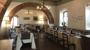 Un espace repas agrémenté d’arches en briques, de lustres et de tables dressées pour le repas.