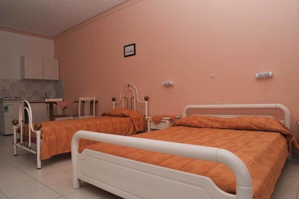 A room with two beds, a small kitchenette, and a single cabinet.
