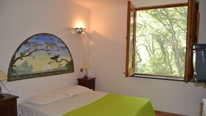 A bedroom with a bed, a nightstand, a lamp, a painting, a window, and a radiator. - Holiday Time Sorrento (Piano di Sorrento)