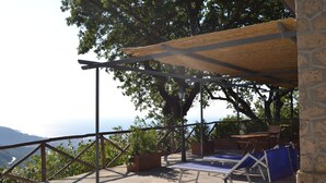 An outdoor terrace with a view of the sea, wooden furniture, and potted plants. - Holiday Time Sorrento (Piano di Sorrento)