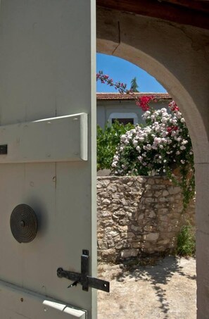 A white door with a metal handle, a stone wall, and a stone archway. - Critamo Cottage (Apokoronas)