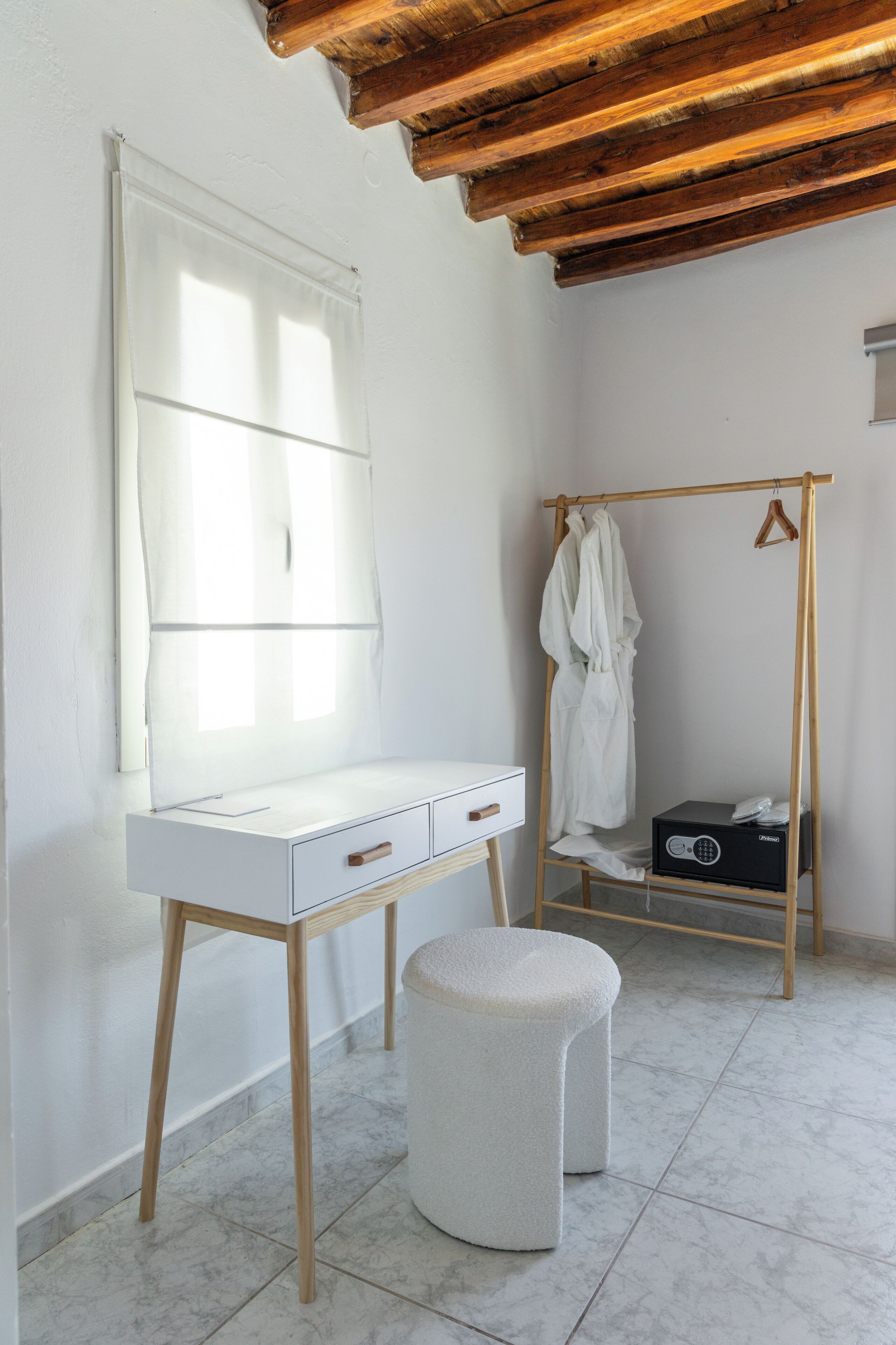 A white vanity with a mirror, wooden legs, and a small stool.