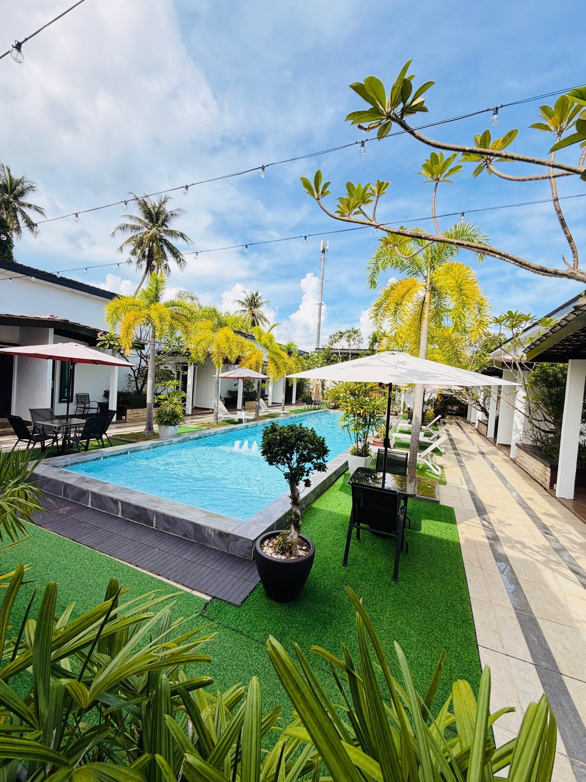 A swimming pool with a surrounding patio area, including outdoor seating and umbrellas.