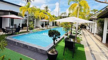 A swimming pool with a surrounding patio area, including outdoor seating and umbrellas.