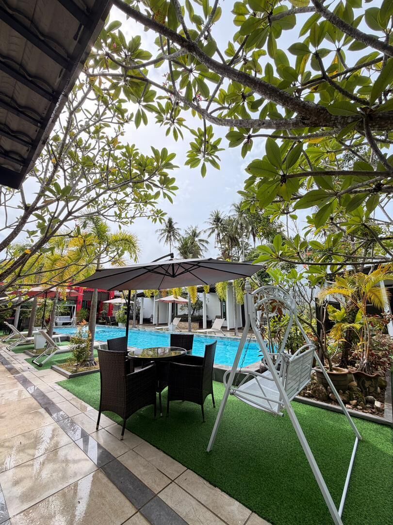 A pool area with artificial grass, a swing chair, and a covered seating area.