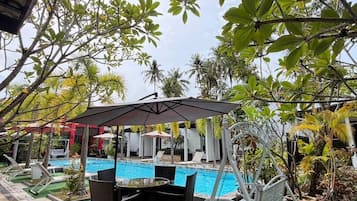 A pool area with artificial grass, a swing chair, and a covered seating area.
