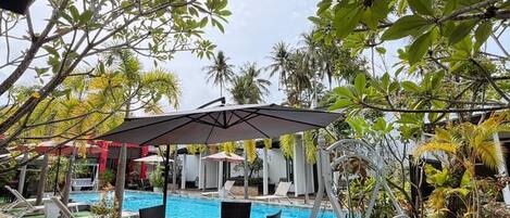 A pool area with artificial grass, a swing chair, and a covered seating area.