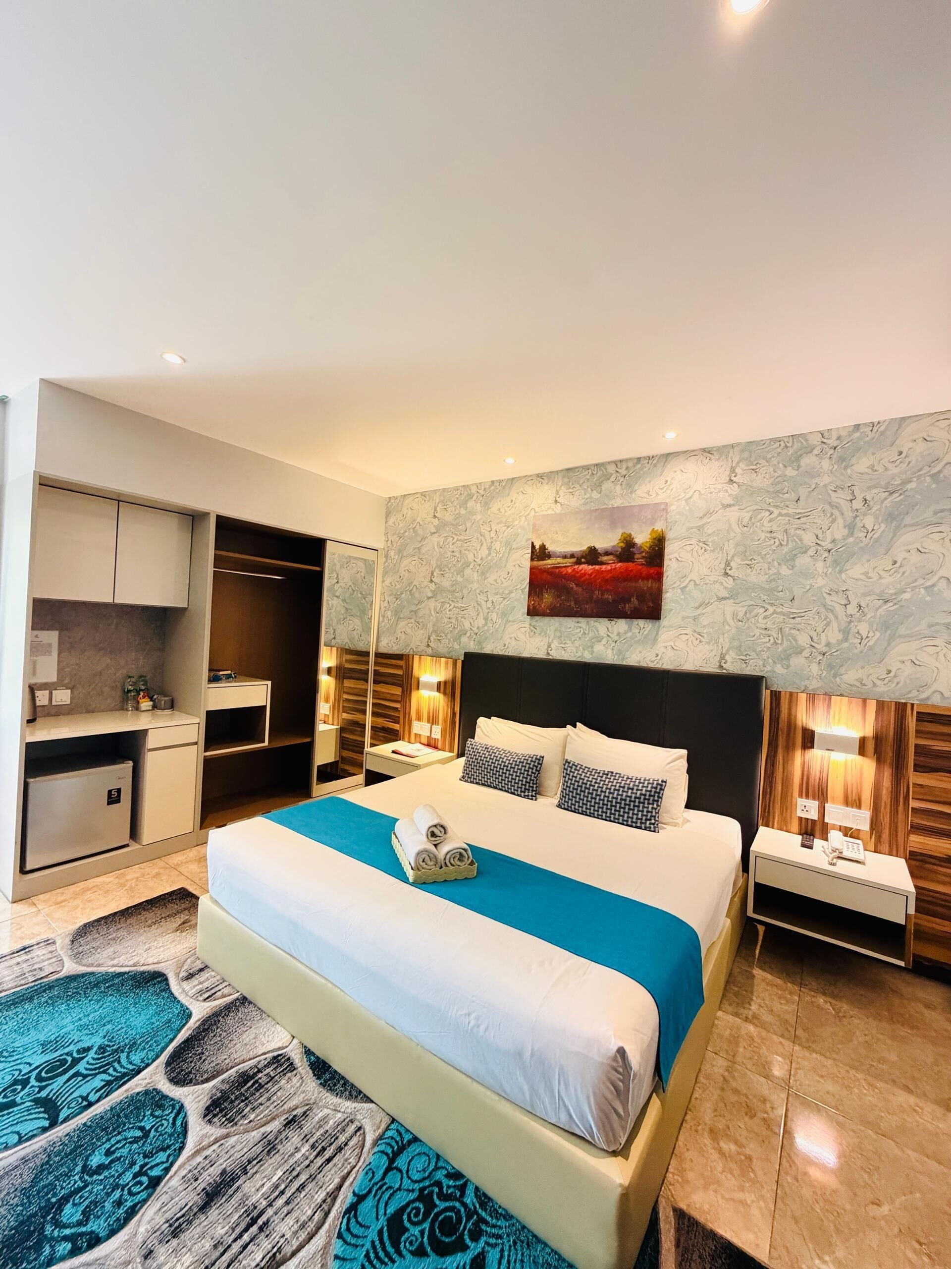 A hotel room with a bed, a desk, a wardrobe, and a bathroom.