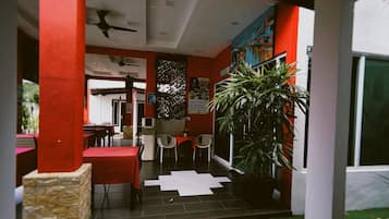 An indoor area with red walls, a tiled floor, and a large potted plant.