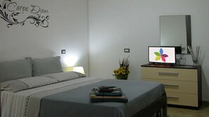 A bedroom with a bed, bedside table, lamp, dresser, mirror, and a wall decal.