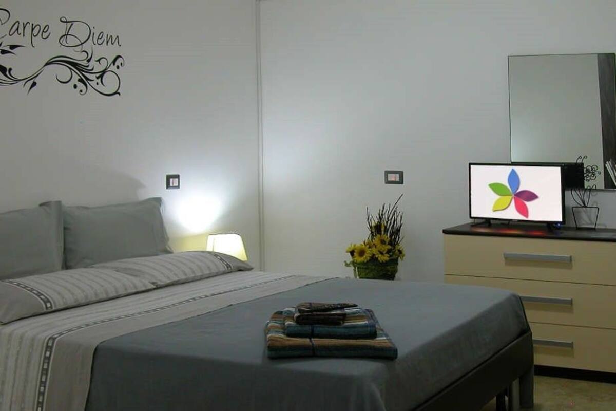 A bedroom with a bed, bedside table, lamp, dresser, mirror, and a wall decal.