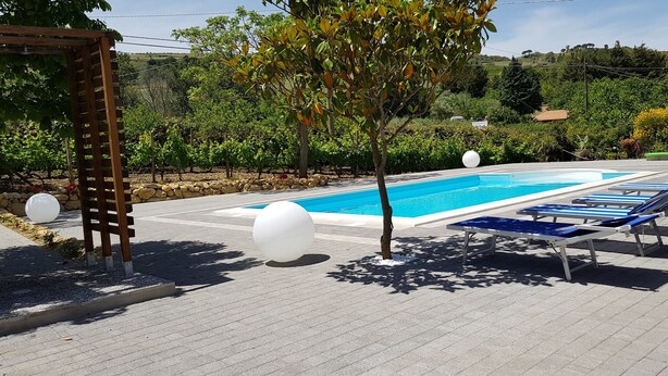 A swimming pool with lounge chairs and a pergola.