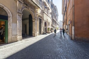 A cobblestone street with historic buildings, storefronts, and outdoor seating areas. - Ara di Marte Suites (Rome)