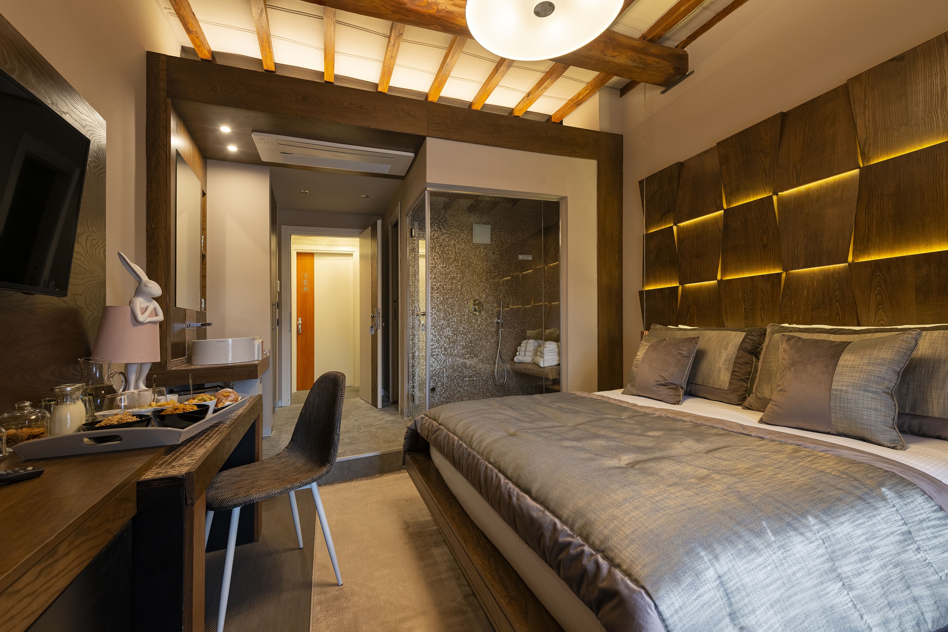 Une chambre moderne avec un grand lit, un bureau avec une chaise, une télévision et un espace douche.