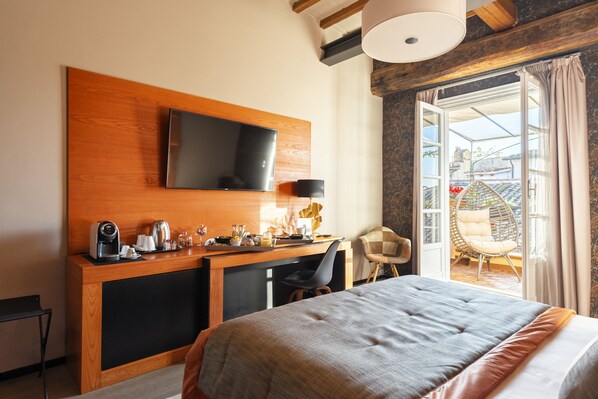 A hotel room with a bed, a desk with a flat-screen TV, a coffee maker, and a chair. - Ara di Marte Suites (Rome)