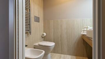 Een moderne badkamer met toilet, hygiëneschuimer en handdoekhouder.