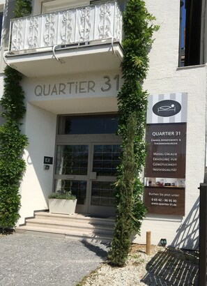A building entrance labeled 'QUARTIER 31' with a signboard detailing amenities and contact information. - Quartier31 (Lieser)