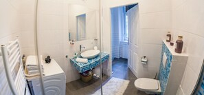 A bathroom with a white sink, a mirror, a toilet, and a shower area. - Vienna Market Apartment (Vienna)