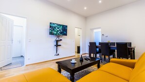 Una sala de estar moderna con un televisor de pantalla plana montado en la pared, una mesa de centro y sillones amarillos.