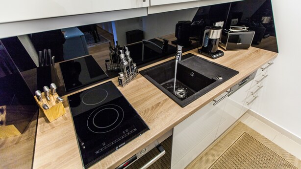 Una cocina moderna con una placa de inducción Bosch, un lavamanos negro y una cafetera.