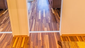 Un pasillo estrecho con suelo de madera que conduce a una sala de estar con sofá y mesa de centro.