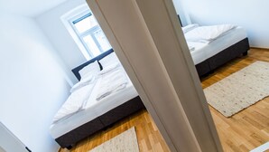 Un dormitorio con dos camas, suelo de madera y un ventanal grande.