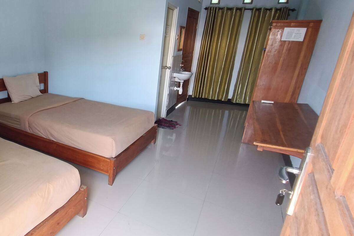 A room with two wooden beds, a sink, and a wooden cabinet.