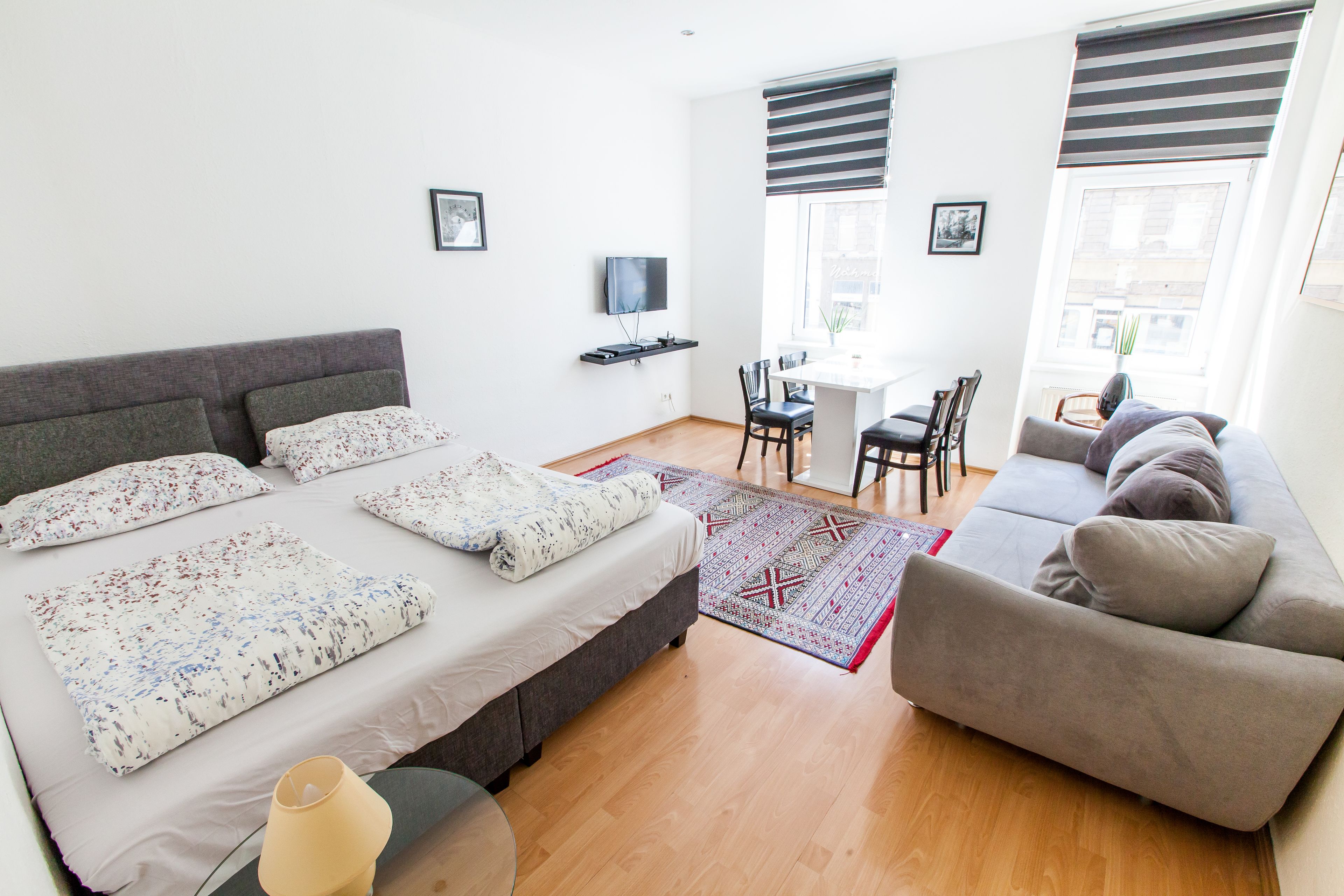 Una camera da letto moderna con un letto, un divano, un tavolo da pranzo e una TV.