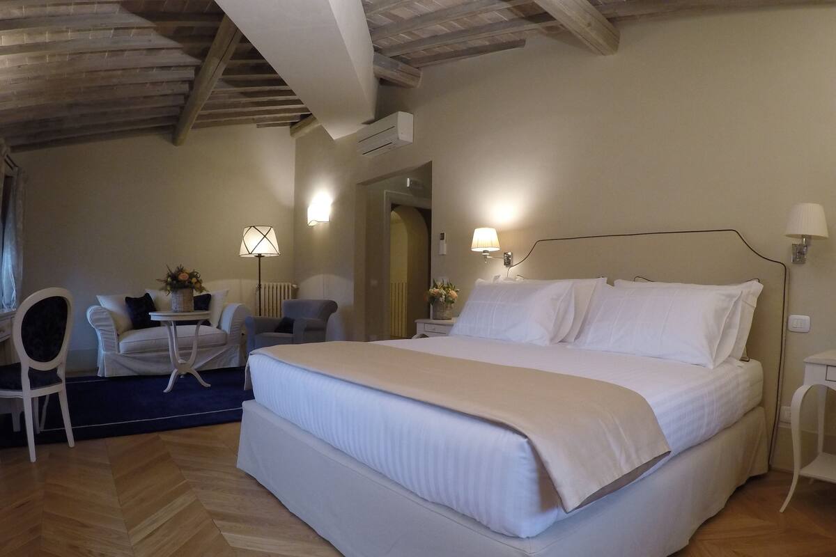 Une chambre d’hôtel avec un grand lit, un bureau, une chaise et une lampe.