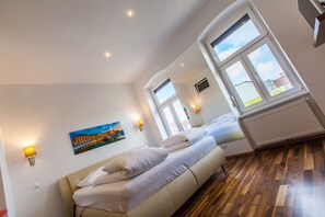 Ein modernes Hotelzimmer mit einem großen Bett, einem Bild an der Wand und Blick auf die Stadt durch die Fenster.