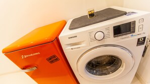 Samsungin digitaalinen invertteripesukone, jonka yläosa on harmaa ja runko oranssi.