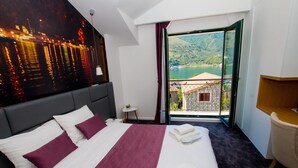 A hotel room with a large bed, a view of a lake, and a balcony. - Hotel Alkima (Kotor)