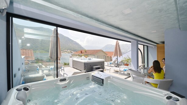 A modern indoor pool area with a hot tub, lounge chairs, and a view of mountains. - Hotel Alkima (Kotor)