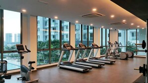 A gym with treadmills, elliptical machines, and a weight bench, large windows with a city view. - Cyberjaya Cybersquare Soho Suites (Cyberjaya)