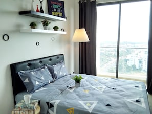Quarto moderno com uma cama grande, mesa de cabeceira, abajur e vista para a cidade pela janela.