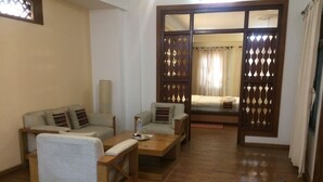 Una habitación con piso de madera, dos sofás, una mesa de centro y una cama con cortina.