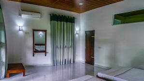A hotel room with two beds, a wooden bench, a mirror, a door, and a window with curtains. - Wildescape Polonnaruwa (Polonnaruwa)