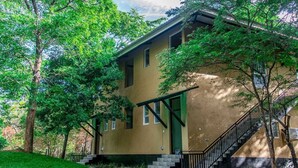 A two-story building with a green door and a staircase leading to the second floor. - Wildescape Polonnaruwa (Polonnaruwa)