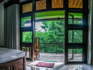 A room with a large window, a wooden chair, and a bed. - Wildescape Polonnaruwa (Polonnaruwa)